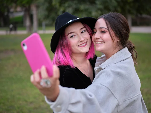 Dvě usměvavé dívky spolu v parku na selfie — Stock fotografie