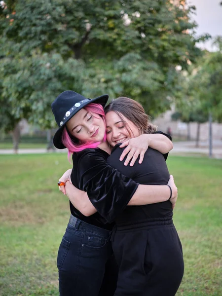 Zwei Freunde in schwarzen Kleidern umarmen sich im Park stehend — Stockfoto