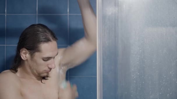 Fiatal fehér hosszú hajú férfi dörzsöli a hónalját és a karját a zuhanyzóban - közelkép lövés — Stock videók