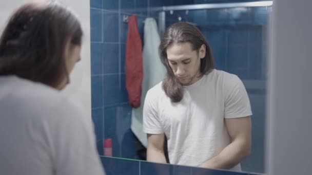Jonge blanke man poetst zijn tanden in de badkamer in de ochtend - Slow motion schot — Stockvideo