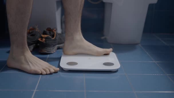 Barefoot man weegt zichzelf in de badkamer als een ochtend routine - Close-up schot — Stockvideo