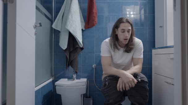 Young caucasian man doing a lot of effort in the bathroom whilst shit - Frontal shot — Vídeos de Stock