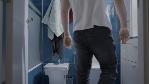 Jovem caucasiano viajando no banheiro e fazendo xixi no banheiro - tiro nas costas — Vídeo de Stock