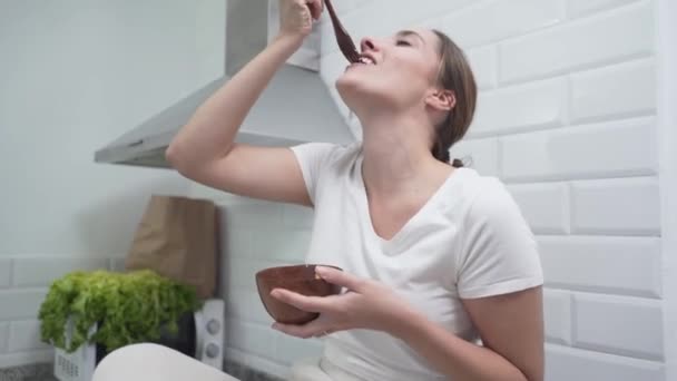 Joyful Woman zingt en gebruikt haar houten vork als microfoon tijdens het eten van maaltijd in de keuken. Sluitingsdatum — Stockvideo