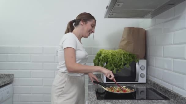 Feliz casera caucásica está cocinando en casa mientras baila. Tiro medio — Vídeos de Stock