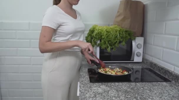 Obraz dziewczyny gotującej danie wegańskie na nowoczesnym palniku elektrycznym. Średni strzał — Wideo stockowe