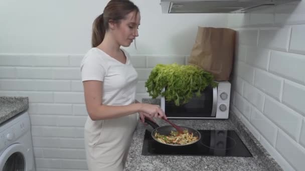 Encantadora ama de casa cocinó plato de verduras saludables y lo colocó en un tazón de madera. Tiro medio — Vídeos de Stock