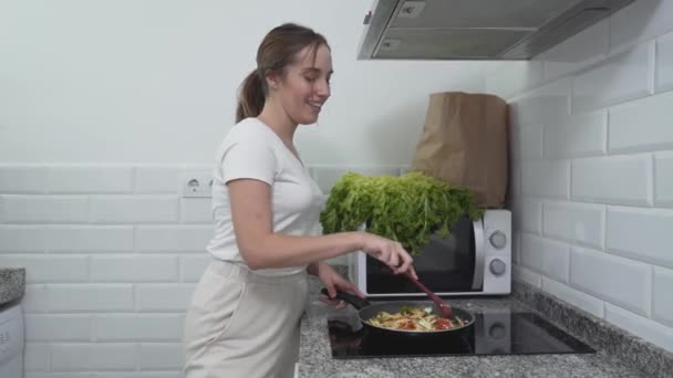 Счастливая девушка поет во время приготовления овощной еды на кухне. Medium Shot — стоковое видео