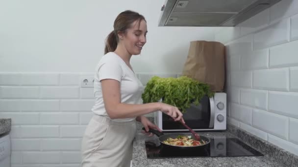 Chica feliz está cantando mientras cocina comida vegetal en la cocina. Tiro medio — Vídeos de Stock