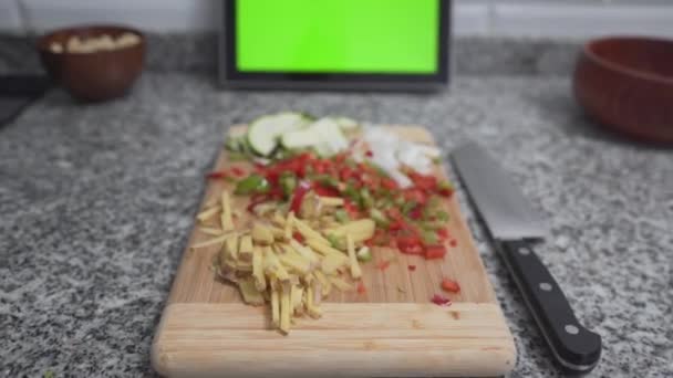 Chopped Veggies On Wooden Board And Bokeh Tablet With Green Screen At Background. Zoom In — Stock Video