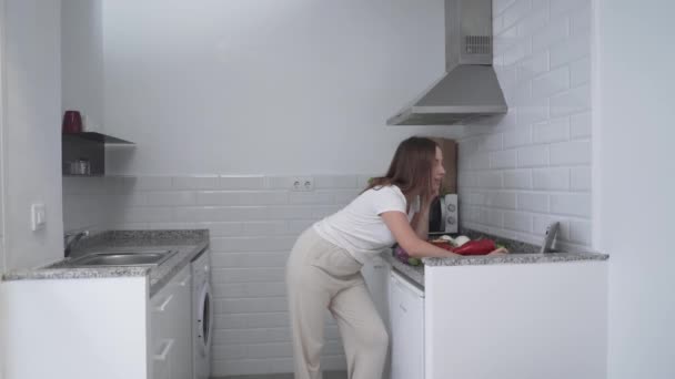 Mujer joven sacando cuchillo y tabla de cortar de un cajón de cocina. - tiro ancho — Vídeos de Stock