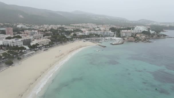 Czysta i turkusowa niebieska woda na plaży Porto Novo - Es Carregador Beach z Yacht Club w deszczowy dzień na Majorce, Hiszpania. - Podnośnik powietrzny — Wideo stockowe