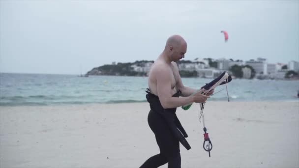 Masculine Man At The Beach Preparing Kite String For Kitesurfing In Mallorca, Spain. tracking shot — Vídeo de Stock