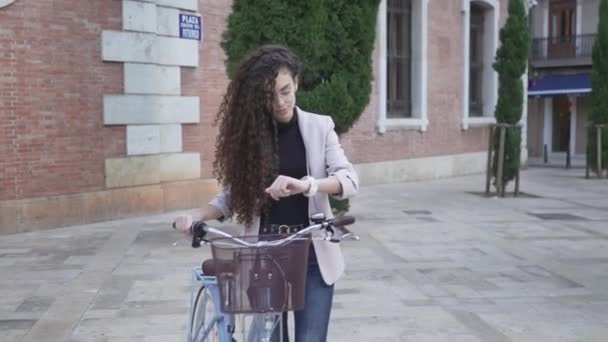 Moroccan Girl Having Long And Curly Hair With Bicycle Is Looking On Her Watch. Handheld — Vídeo de Stock