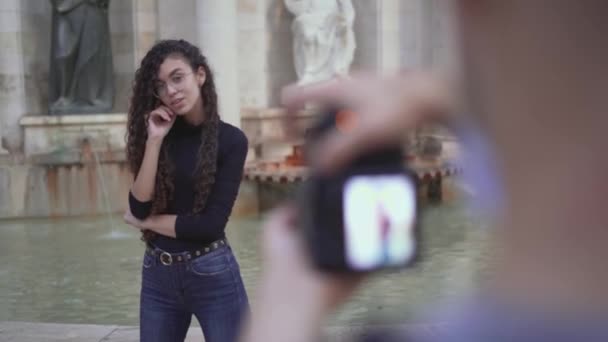 Pantalla de la cámara en poder de un fotógrafo masculino que toma fotos de una joven dama marroquí al aire libre. foco de rack — Vídeos de Stock