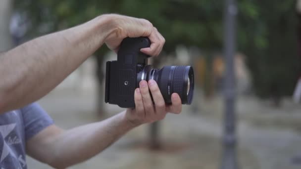 Photographer Holding A Modern Camera Outdoor On Bokeh Background. Closeup — стоковое видео