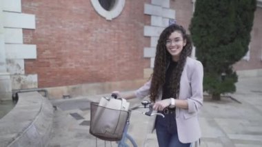 Beautiful Moroccan Lady With Long Curly Hair Posing With A Bicycle Outdoor. zoom-out