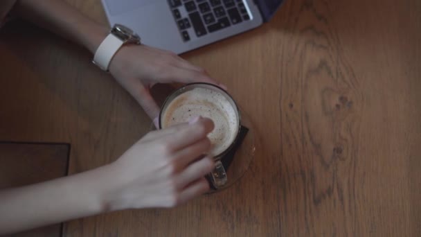 Frau rührt heißes Kaffeegetränk an, während sie am Laptop im Tisch arbeitet. - hoher Winkel — Stockvideo