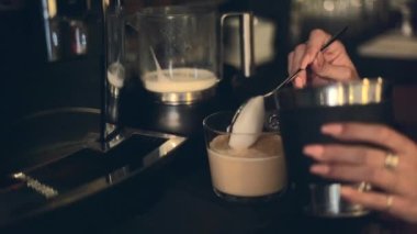 Female Hands Scooping Frothed Milk On Top Of Warm Coffee In The Office. close up