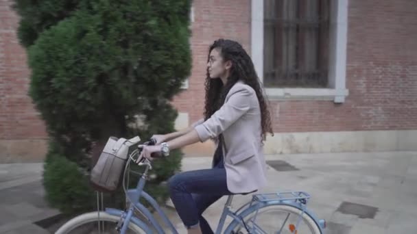 Moroccan Girl Wearing A Coat Biking Towards City Fountain. - close up — стоковое видео