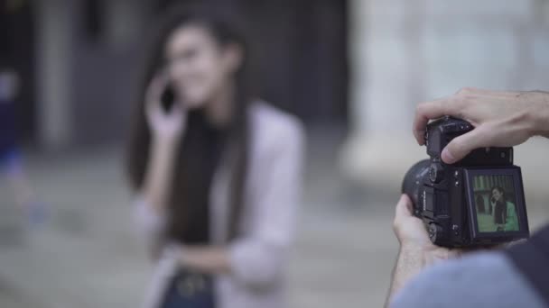 Fotógrafo tomando fotos de una chica hablando por teléfono. - enfoque rack — Vídeo de stock