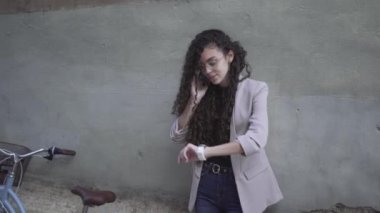 Young Moroccan Woman Making A Phone Call Then Looked At The Time On Her Wristwatch. - medium shot