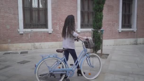 Curly-Haired Lady With Bicycle Is Walking Along The Sidestreet Of City Park. Tracking Shot — Vídeo de Stock