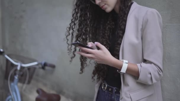 Curly-Haired Moroccan Lady Smiling While Looking On Her Smartphone. Sideview — Vídeo de Stock