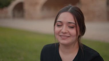 Kahverengi saçlı, el sallayan ve utanarak gülen çekici genç bir kadın. Kapat.