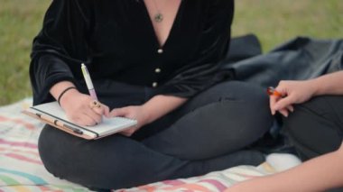 close up on girl hand writing on a notepad while sit on ground. Old fashioned custom