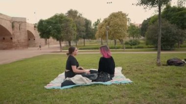 friends chatting in a relaxing moment in the park at daytime. Push in, wide view