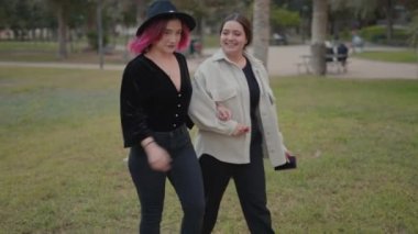 stylish smiling friends walking in the park holding hands. slowmotion