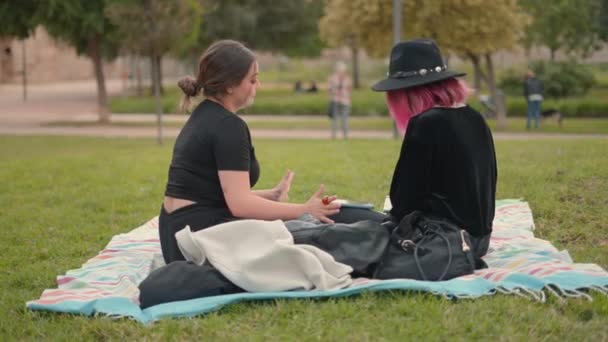 Side view of two girls on black clothing interacting at the park area. Leisure and companionship, casual — Stockvideo
