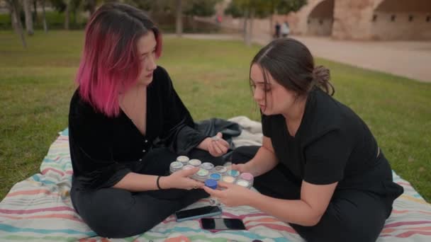 Молоді дівчата тримають кольорову палітру для макіяжу, обговорюючи, який вибрати — стокове відео