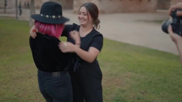 Fotógrafa grabando dos jóvenes modelos femeninas abrazándose calurosamente — Vídeos de Stock