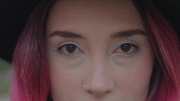 Brown eyeballs, pink hair and pierced nose. Make up concept, stylish and beauty. Extreme close up — Wideo stockowe