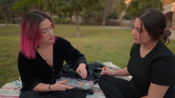 Two european friends talking about cosmetics in a park. Friendship concept, feminine fashion — стоковое видео