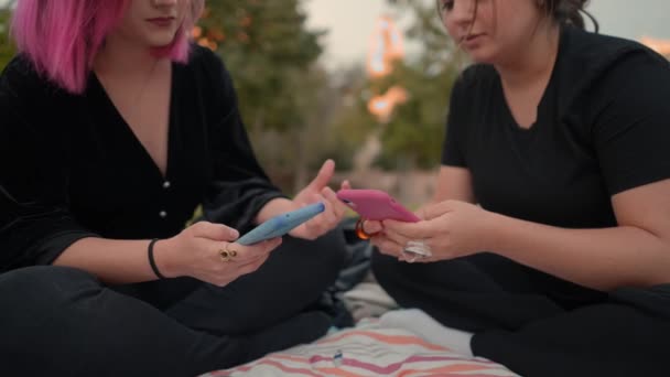 Girls in the public park using smartphones and texting on it, close up view — Wideo stockowe