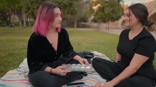 Friends in the park having a conversation about makeup palette colors. Fashion and style concept — стоковое видео