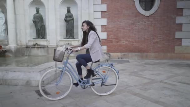 Marockansk kvinna med lång svart lockigt hår ridning en cykel i parken. spårningsskott — Stockvideo