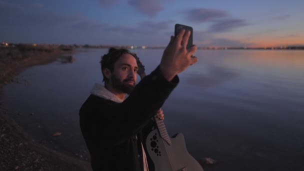 Guitariste barbu espagnol prendre une photo selfie avec sa guitare au coucher du soleil par Torrevieja Pink lake à Alicante, Espagne — Video