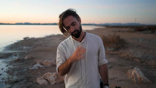 Homme hipster espagnol avec guitare marchant au bord du lac Torrevieja Pink au coucher du soleil, Alicante — Video