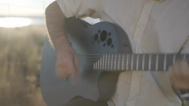 Homme hispanique jouant de la guitare et chantant contre la lumière du soleil à l'extérieur — Video