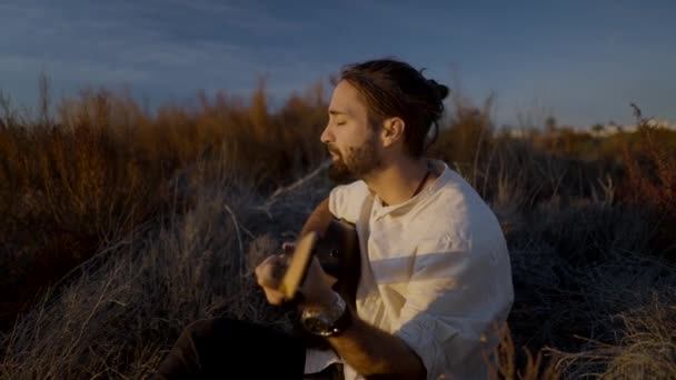 Homme musicien jouant de la guitare et chantant au soleil couchant champ en automne — Video