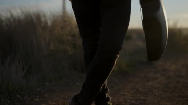 Attraktiver bärtiger kaukasischer Mann mit Gitarre im Stehen und Blick in die Kamera, nachdem er das Telefonat beendet hat, beleuchtet mit Sonnenuntergang — Stockvideo