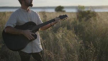 İspanyol gitarist sonbaharda çayırlarda akor çalıp Torrevieja Pembe Gölü yakınlarındaki siyah akustik gitarda şarkı söylüyor.