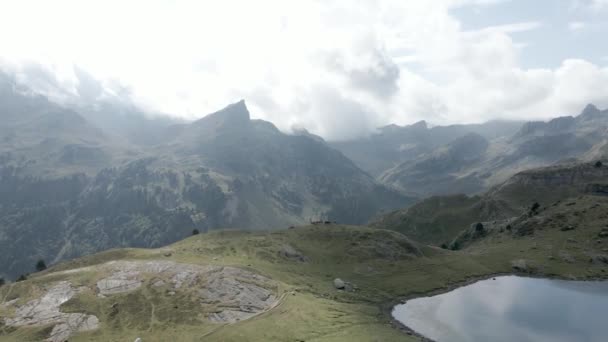 Movimiento aéreo hacia atrás disparado sobre el lago Ayous y la hermosa cordillera de los Pirineos en Francia en un día nublado. — Vídeos de Stock