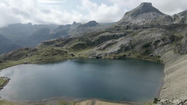 Aerial drone view over the lake Ayous and the surrounding mountain range in the Pyrenees in France on a bright sunny day. — Stock Video