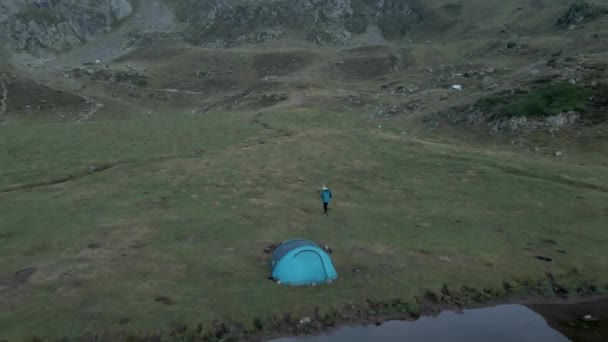 曇り空の日にフランスのピレネー山脈のAyous湖の横に青いテントのあるキャンプ場の上空の空中ドローンの眺め. — ストック動画