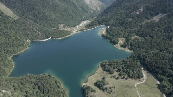 Luchtfoto doorkijkend over het Ayous meer omgeven door weelderige groene vegetatie aan alle kanten in de Pyreneeën in Frankrijk op een zonnige ochtend. — Stockvideo